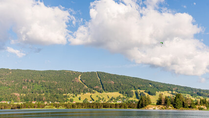 Paragliding Over Lac des Rousses in Summer. Landscape of lake, forest and mountain. Les Rousses, Jura, France.