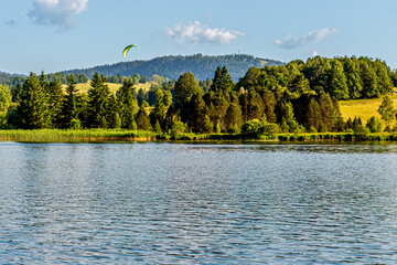 Paragliding Over Lac des Rousses in Summer. Landscape of lake, forest and mountain. Les Rousses, Jura, France.