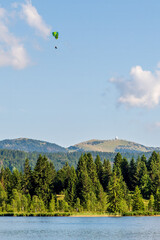 Paragliding Over Lac des Rousses in Summer. Landscape of lake, forest and mountain. Les Rousses, Jura, France.