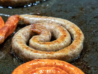 assorted pork sausages and beef rolled into a circle grilled