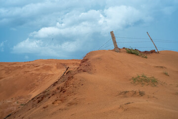 Tourists climbing the red sand dunes of Mui Ne under a blue sky