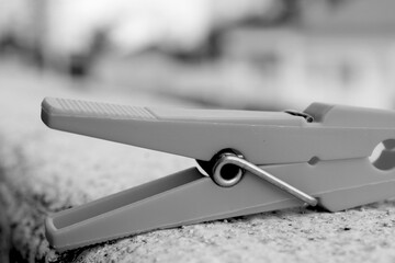 Everyday Geometry: Clothespin in Focus
A simple plastic clothespin lies on a textured, painted surface, captured in crisp black and white. This minimalist composition transforms an ordinary household