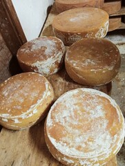 view of an inside of a dairy with racks full of forms of cheese