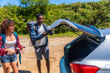 Hikers preparing backpacks for road trip, opening car trunk