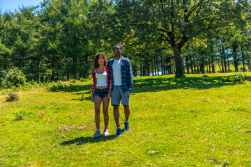Young tourists couple walking in green meadow on sunny day