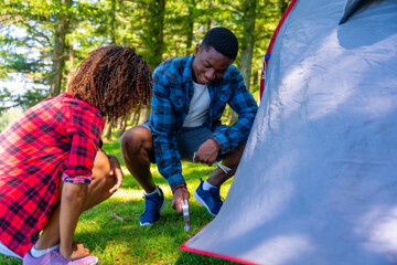 Couple setting up tent while camping in nature
