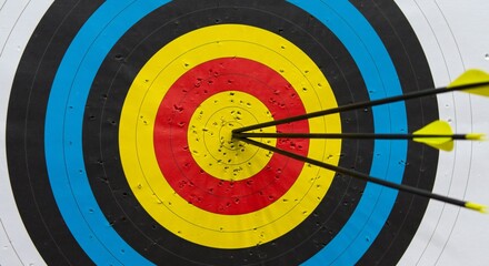 Archery target with concentric circles in vivid colors; three arrows striking the center, emphasizing accuracy. Bright lighting highlights details of the target and arrows.
