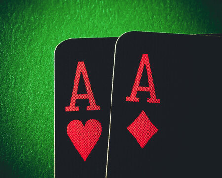 A pair of aces on a green background, close up shot. Ace of hearts and ace of diamonds. Nuts hand a pair of aces to win. Close-up image a pair of aces.