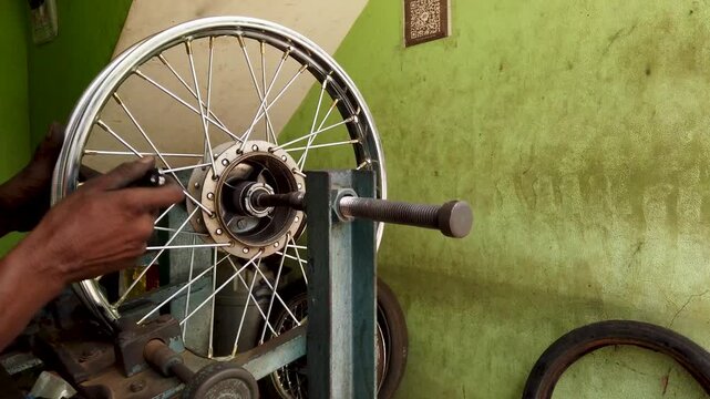 Mysuru, Karnataka, India-July 20 2025; A motorcycle wheel rim is being repaired with Jigs and fixtures, workshop, spokes, stainless steel, metal, hub, bearings at a auto garage in Mysore, India.
