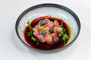 Colorful and Fresh Tuna Tartare with Blueberries and Herbal Garnish in a Vibrant Red Sauce,...