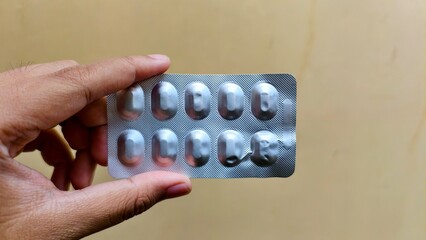 Holding a Blister Pack of Pills Against a Neutral Background, Aluminum Blister Pack of Ten...