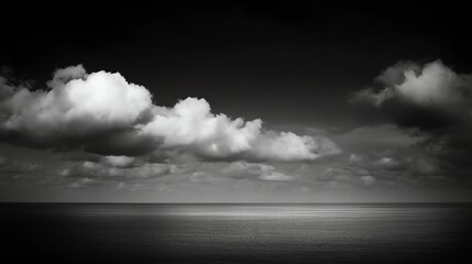 Black and white photo showcasing a dramatic sky with billowing clouds over a calm, reflective ocean horizon.