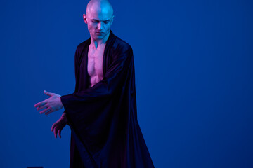 A striking image of a man in a flowing black robe, expressing dynamic movement against a vibrant...