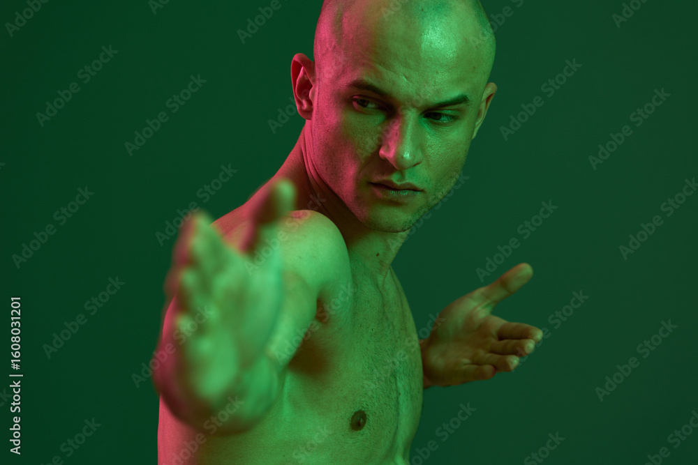 Poster athletic man posing with a strong expression, showcasing a dynamic silhouette against a green backdr