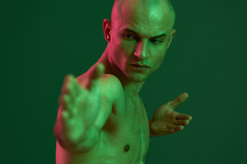 Athletic man posing with a strong expression, showcasing a dynamic silhouette against a green...