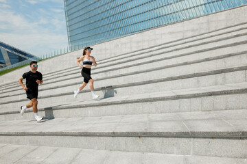 Couple running up modern steps in urban setting while enjoying fitness