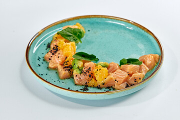 A Fresh and Colorful Salmon Dish Artfully Arranged with Orange Segments and Leafy Greens on a...