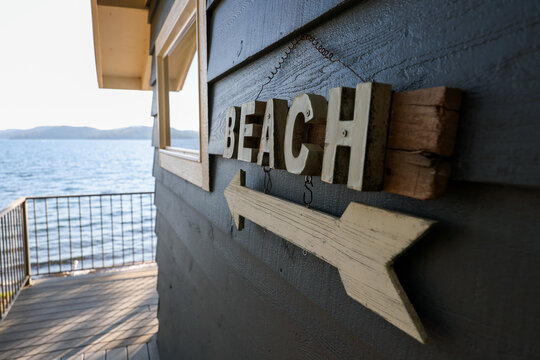 Decorative sign on a lake front vacation home that says beach with a wooden arrow pointing toward the water