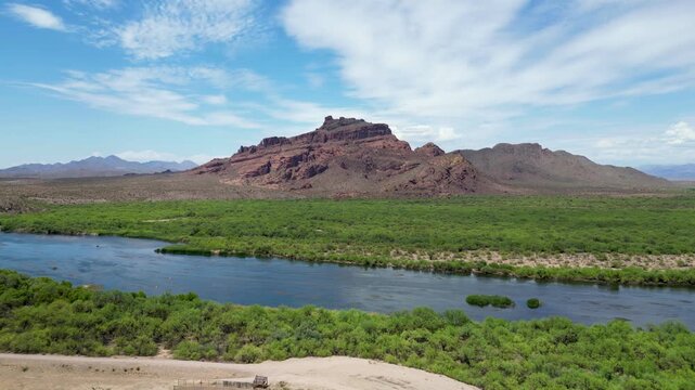 Aerial footage of the Red Mountain framed by lush riverbank in Gold Canyon town in Arizona, USA