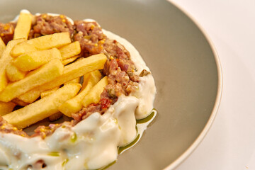 Savory Plate Featuring Juicy Ground Meat Topped with Creamy Sauce Accompanied by Crispy French Fries on a Stylish Dinner Plate
