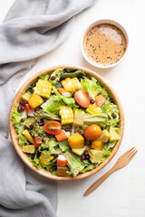Top view of colorful vegetable salad in wooden bowl with Japanese sesame dressing on white background, Healthy, fresh, plant based eating concept