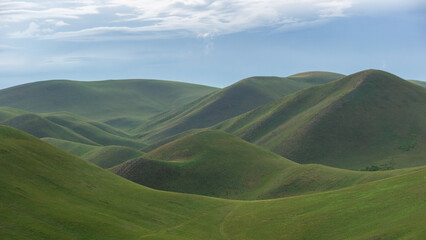 Lush green rolling hills under a bright blue sky, showcasing the beauty of nature's landscape, with...