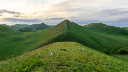 Lush green rolling hills under a cloudy sky, showcasing the beauty of nature, with vibrant grass and gentle slopes creating a serene landscape for outdoor enthusiasts