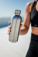 Stainless steel water bottle held by a fitness enthusiast during workout