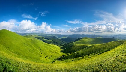 Naklejka premium scenic panoramic view of lush green hills and distant mountains under a bright blue sky with fluffy clouds showcasing natural beauty and tranquility concept