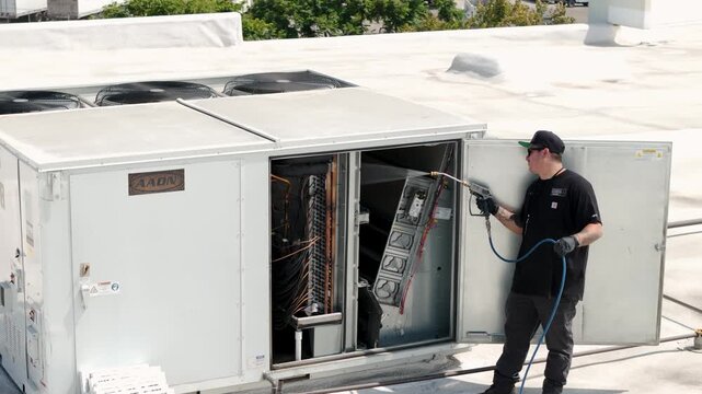 HVAC Technicians Pressure Washing Rooftop AC Units on Commercial Building