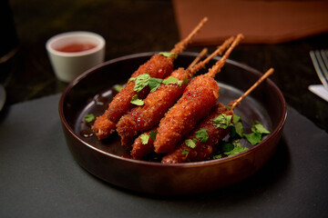 A Delicious Platter of Crispy Skewered Snacks Garnished with Fresh Herbs Served with a Tangy Dipping Sauce for a Perfect Culinary Experience