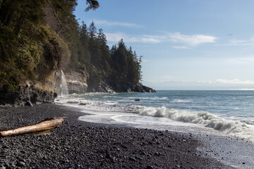Waves breaking on a beach with waterfall flowing into the sea