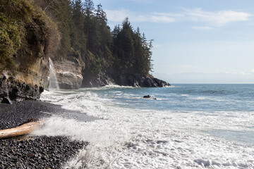 Waves breaking on a beach with waterfall flowing into the sea