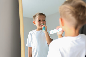 Cheerful young boy brushing teeth in bathroom. Morning hygiene routine, dental care and healthy...