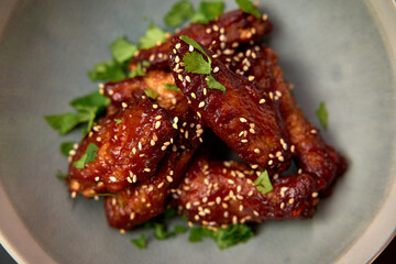 Deliciously Glazed Sesame Chicken Wings Topped with Fresh Herbs, Perfectly Cooked and Ready to...