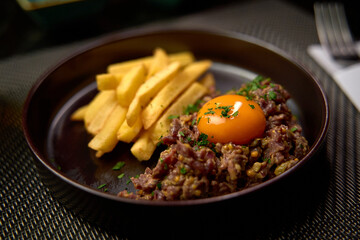 Delicious Plate of Beef Tartare with Egg Yolk and Crispy French Fries Garnished with Fresh Parsley, Perfect for Gourmet Dining Experiences