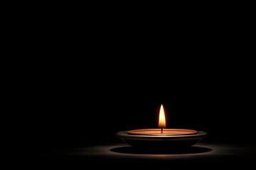 A single candle flame burns in the dark, a powerful symbol of hope, remembrance, mourning, and faith.

