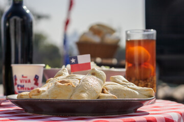 Chilean Independence Day: Traditional empanadas with Chilean flag and mote con huesillo on a red tablecloth