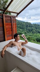 Handsome Man Relaxing on Holiday with Lush Green Valley and Misty Mountain Views in Chiang Mai, Thailand