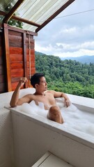 Handsome Man Relaxing on Holiday with Lush Green Valley and Misty Mountain Views in Chiang Mai, Thailand