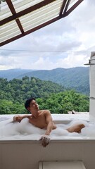 Handsome Man Relaxing on Holiday with Lush Green Valley and Misty Mountain Views in Chiang Mai, Thailand