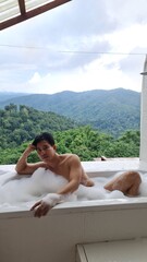 Handsome Man Relaxing on Holiday with Lush Green Valley and Misty Mountain Views in Chiang Mai, Thailand