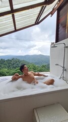 Handsome Man Relaxing on Holiday with Lush Green Valley and Misty Mountain Views in Chiang Mai, Thailand