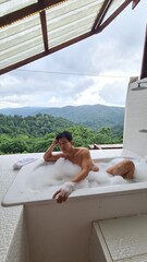 Handsome Man Relaxing on Holiday with Lush Green Valley and Misty Mountain Views in Chiang Mai, Thailand