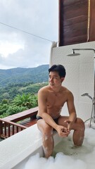 Handsome Man Relaxing on Holiday with Lush Green Valley and Misty Mountain Views in Chiang Mai, Thailand