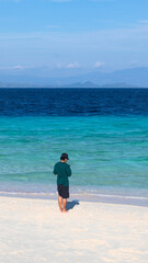 Person Standing on White Sand Beach by Ocean