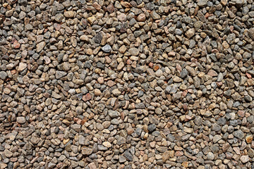 Natural gravel stone texture in earthy tones, ideal for construction, landscaping or design backgrounds. Rough surface with small rocks creating a gritty and organic outdoor ground pattern.