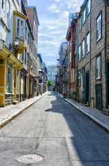 Charming street in Old Quebec with historic buildings, colorful facades, and a bright summer sky. Perfect for travel, editorial, or architectural design concepts. Peaceful and timeless atmosphere.