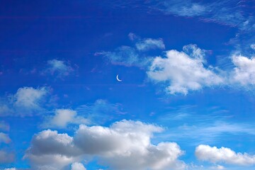 A vibrant sky with clouds and a crescent moon