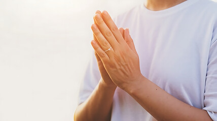 Hopeful hands clasped together in prayer, bathed in warm golden sunlight, conveying peace and spirituality.